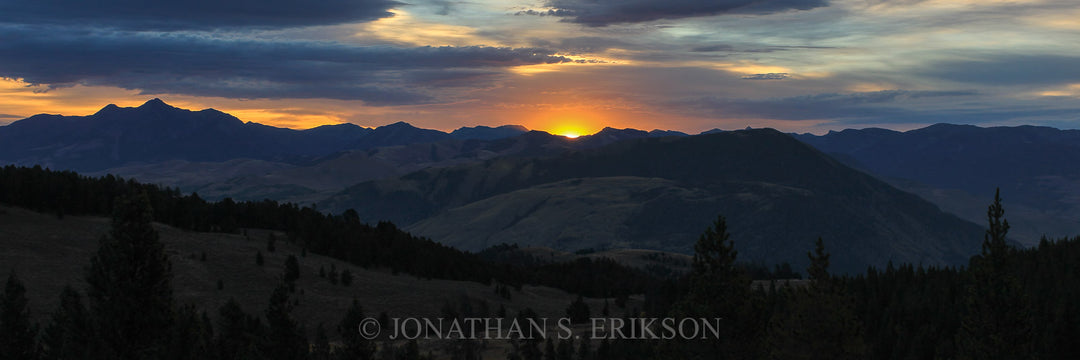 Sunrise over Absaroka mountain range with silhouetted trees in Montana.